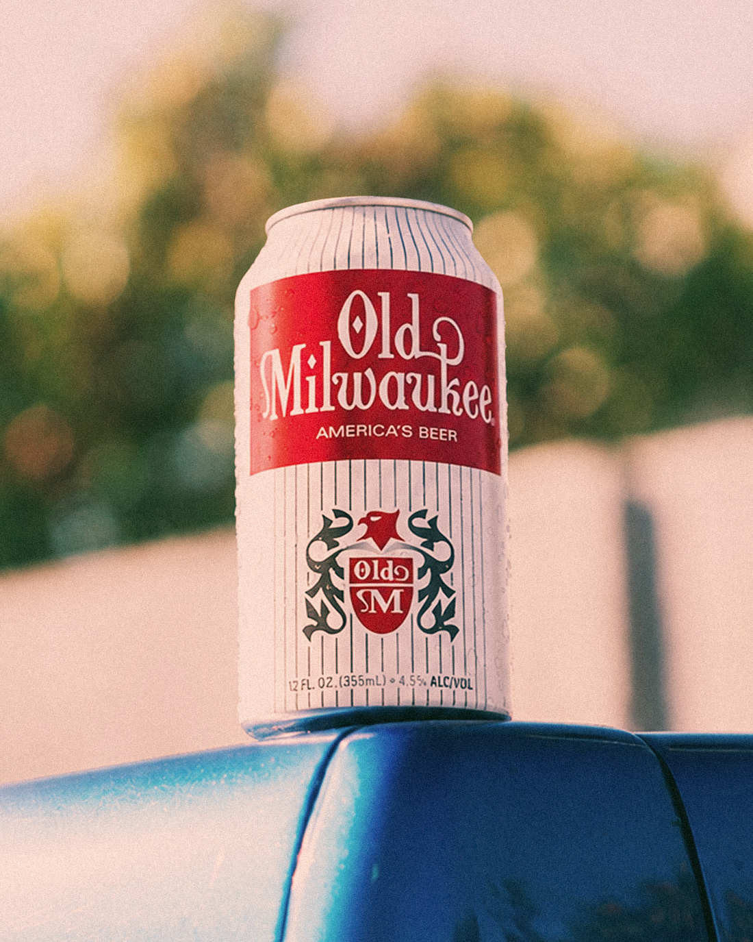 Old Milwaukee beer can on a car with a blurred green background